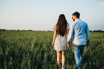 Couple walking on sunny field holding hands