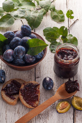 Fresh plums with homemade jam on wooden table