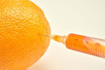 Close-up shot of syringe in ripe orange with glossy peel extracting liquid and showing liposuction...