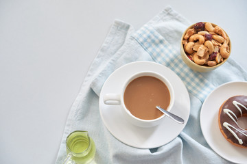 From above shot of composed dessert of glazed doughnut with bowl of nuts and cup of coffee on table