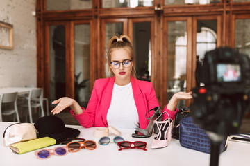 Disappointed girl in glasses and pink jacket recording new fashion video for her vlog