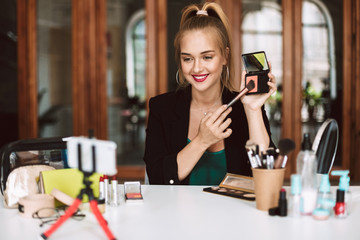 Beautiful beauty blogger happily showing how to make up while recording new video for vlog