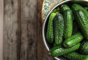 Bowl with ripe fresh cucumbers on table, top view