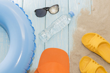 summer vacation on the beach. Yellow flip-flops and swimming circles, bottle and sunglasses.