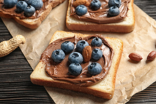 Toast bread with chocolate spread and blueberry on dark background, closeup