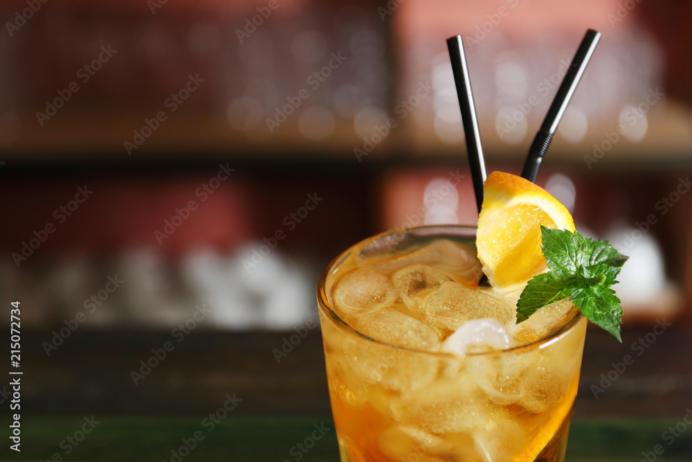 Wall mural glass of delicious cocktail with ice on blurred background, closeup