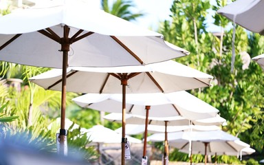 White fabric of beach and swimming pool umbrellas closeup outdoor tropical blur background