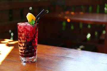 Glass of delicious cocktail with ice on table in bar