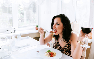 girl eating pasta in a restaurant washing down her red wine