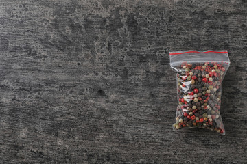 Plastic bag with spice on grey background, top view