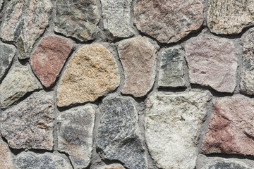 Neatly stacked rough cut stone wall texture background.