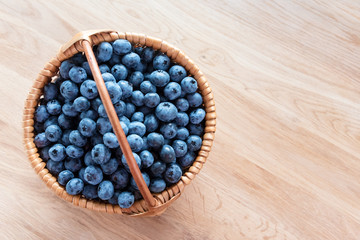 Blueberry in basket on wooden table background. Ripe and juicy fresh picked blueberries closeup, top view