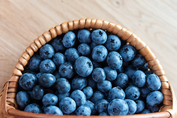 Blueberry in basket on wooden table background. Ripe and juicy fresh picked blueberries closeup, top view