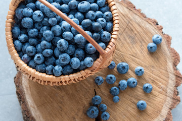 Blueberry in basket on wooden table background. Ripe and juicy fresh picked blueberries closeup, top view