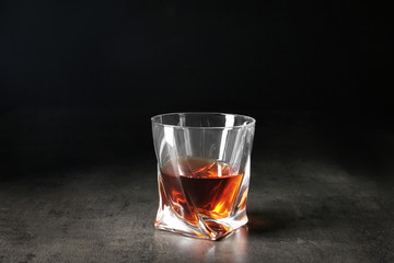 Glass of whiskey on table against dark background