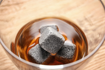 Glass with liquor and whiskey stones on table, closeup