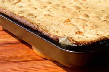 Baked apple pie in a pan on a wooden background