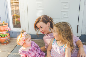 afternoon mom and two daughters on the threshold of the house