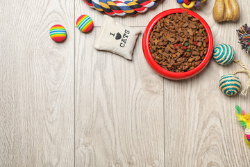 Bowl with food for cat or dog and accessories on wooden background. Pet care