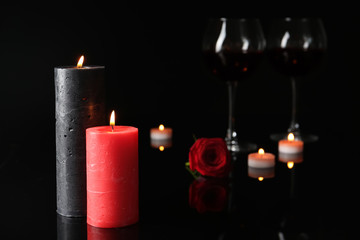 Burning candles and glasses with wine in darkness