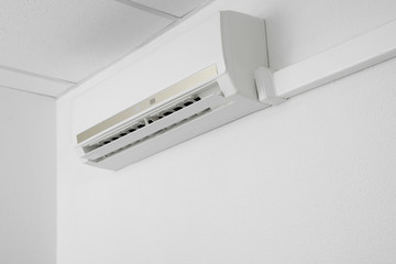 Modern air conditioner on white wall indoors