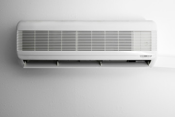 Modern air conditioner on white wall indoors