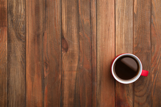 Ceramic cup with hot aromatic coffee on wooden background, top view