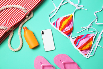 Flat lay composition with smartphone and beach objects on color background