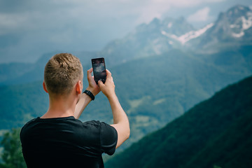 young man photographing smartphone mountain peaks