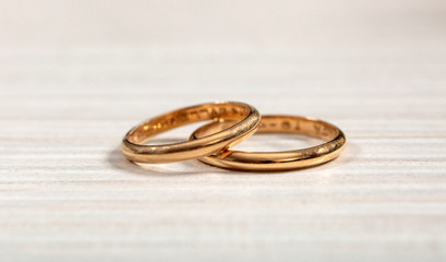 Two golden wedding rings on white wooden background