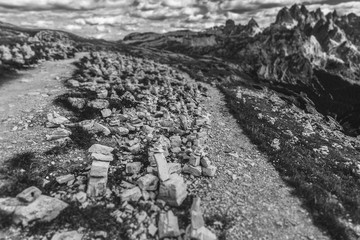 Fototapeta premium Black and white effect of Cairns near a path at the foot of the Tre Cime di Lavaredo, with Cadini di Misurina background, Dolomites, Italy