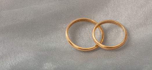 Two golden wedding rings on white silver background, copy space