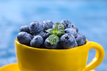 Fresh blueberries in a yellow bright cup and blue background.Concept  Healthy Food. Diet Nutrition .selective focus.