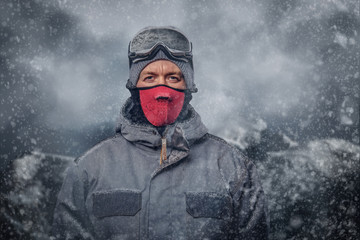 Portrait of a snowboarder dressed in a full protective gear for extream snowboarding posing at a...