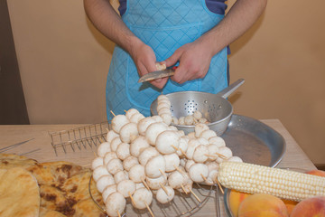 Male hands cuts mushroom with knife, apron on background. Cooking process concept. Cook burgundy...