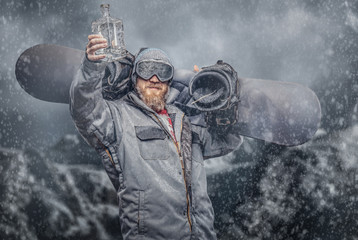 Redhead snowboarder with a full beard in a winter hat and protective glasses dressed in a...