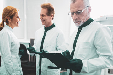 Monthly report. Aged prosperous chemist feeling satisfied while checking monthly report of his...