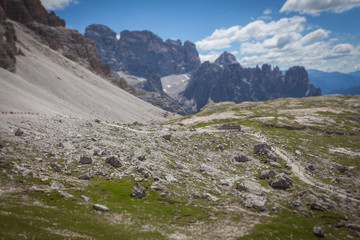 Tilt shift effect of column of tourists walking along a path, with a beautiful dolomitic landscape...