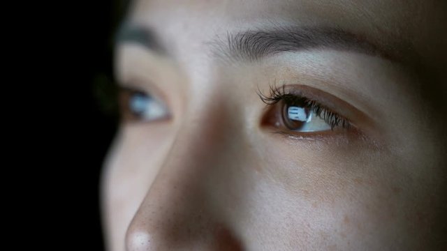 Close up of girl's eye surfing internet at night.