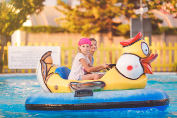 Obraz na płótnie Canvas Two young girls floating in a kids' bumper boat