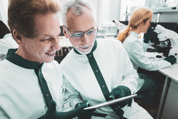 Male biologists. Two prosperous smart male biologists feeling busy while standing near woman in...
