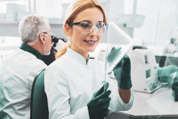 Molecular formula. Female promising chemist wearing glasses writing molecular formula on glass board