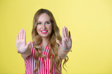 beautiful young girl in a shirt on a yellow background with a gesture of hands