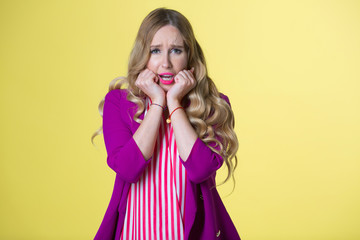 beautiful young girl in a purple jacket on a yellow background with a frustrated face