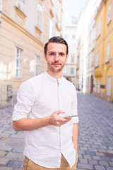 Obraz premium Man tourist with cellphone in Europe street. Caucasian boy looking at camera outdoor