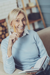 Obraz premium Enjoy your weekend. Cheerful retirement keeping smile on her face while holding her notebook in left hand