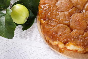 Apple Tarte Tatin - classic French upside-down tart. Whole fruit pie on white table. Rustic style.