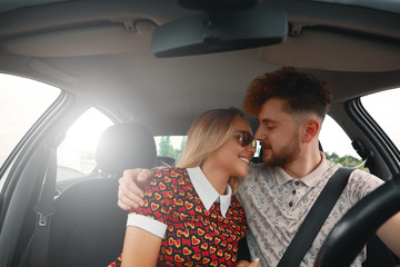 Young couple sitting on the front passenger seats and smiling wh