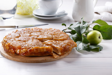 Apple Tarte Tatin - classic French upside-down tart. Whole fruit pie on white table. Rustic style.