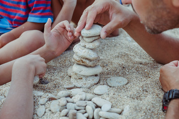 Child's hand  building stone pyramid  with dad 